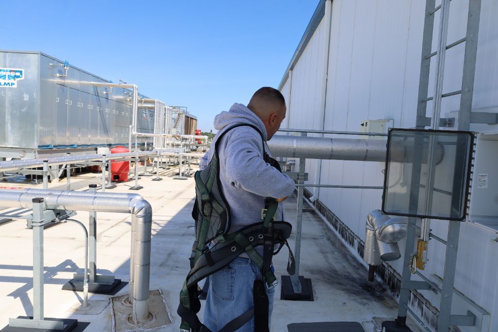 Technician in safety harness servicing refrigeration equipment on the rooftop of Mid Eastern Cold Storage